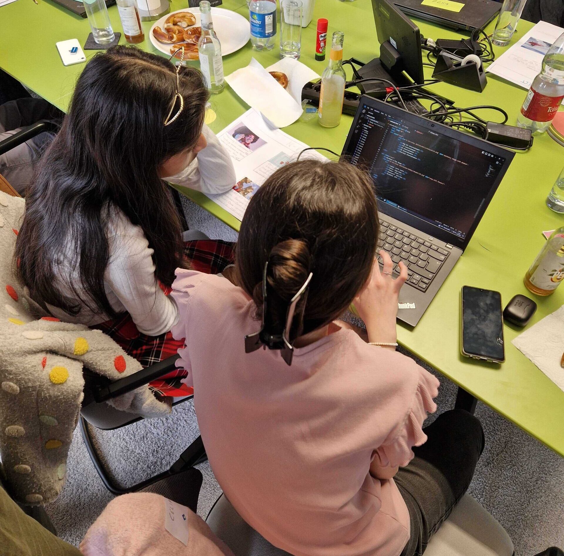 Zwei Mädchen sitzen vor dem Laptop und implementieren in einer Entwicklungsumgebung ihren Blog